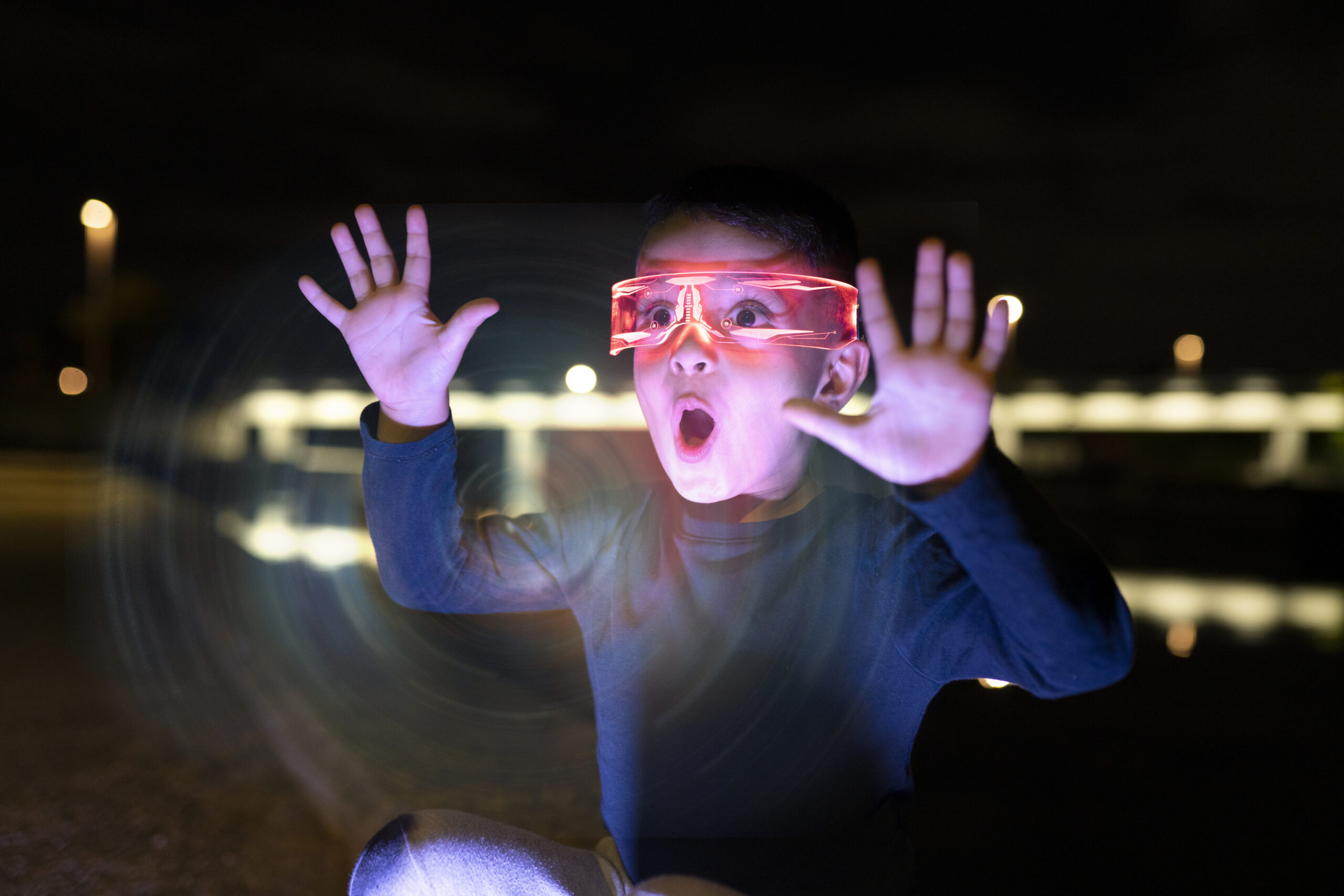 surprised little boy with futuristic glasses with light, he is playing in the simulator - metaverse concept -